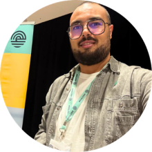 Person wearing an Englobe lanyard and casual work attire standing indoors beside an Englobe banner with teal and yellow colors.