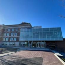 Exterior view of Victoria High school building featuring a modern glass entrance addition connected to a historic brick structure, set under a clear blue sky.