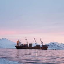 A cargo boat in the arctic ocean at sunset