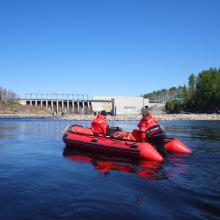 2 men in a zodiac with dam