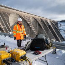 Roseline Levesque standing in front of job site with a large bridge