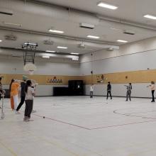 Youth playing lacrosse in a community gymnasium