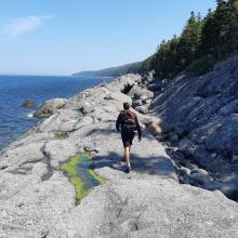 Marion Richard walking on a cliffside beside the water