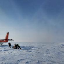 picture of a project in Artic with plane and crew working in snow with blue sky