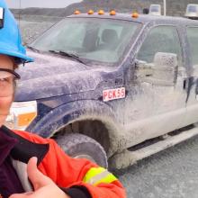 Selfie of Lydia Charbonneau on field with safety equipment with truck in background