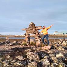 Photo of Lydia Charbonneau next to a big inukshuk in Nunavik