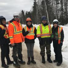 photo of indigenous people smiling wearing EPI on a snowy road lined with trees