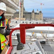 Aerial lift positioned beside a historic brick façade during an exterior building inspection overlooking Parliament Hill.