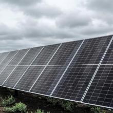 A large array of solar panels in a solar farm under an overcast sky, showcasing renewable energy technology and sustainable power generation.