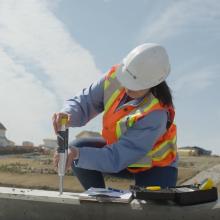 Lindsay Freckleton conducting material testing on a concrete surface at a construction site using measurement tools.