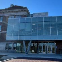 Exterior view of Victoria High School building featuring a modern glass entrance addition connected to a historic brick structure, set under a clear blue sky.